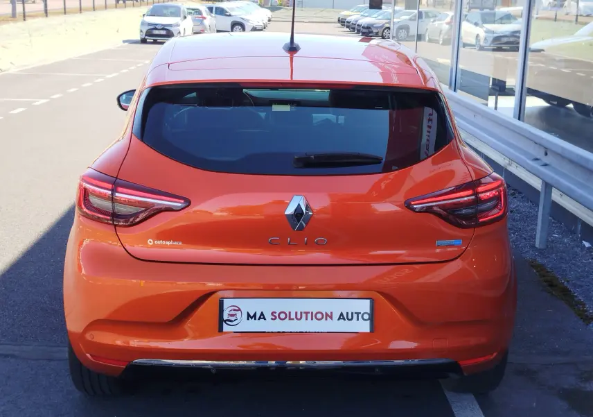 Vue arrière d'une Renault Clio 1.6 E-Tech hybride 2022 en Orange Valencia, avec feux LED et logo distinctif.