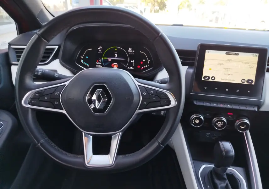 Vue intérieure centrée sur le volant noir de la Renault Clio hybride avec tableau de bord numérique et écran tactile.