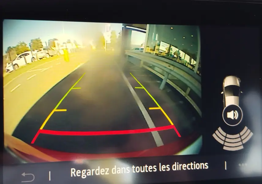 Vue caméra de recul de la Renault Clio orange Valencia, montrant les lignes d’aide au stationnement arrière.