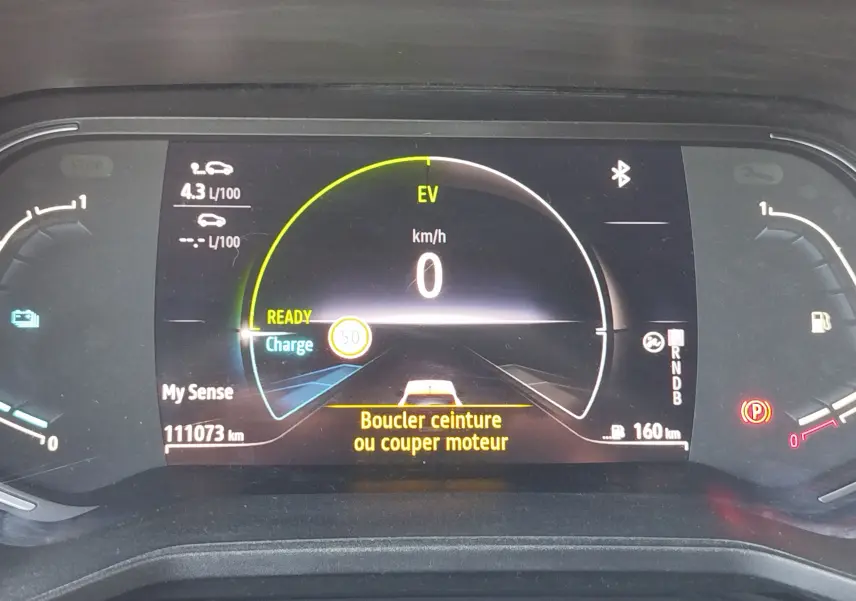Tableau de bord numérique de Renault Clio hybride 2022 affichant vitesse zéro, autonomie 160 km et message de sécurité ceinture.
