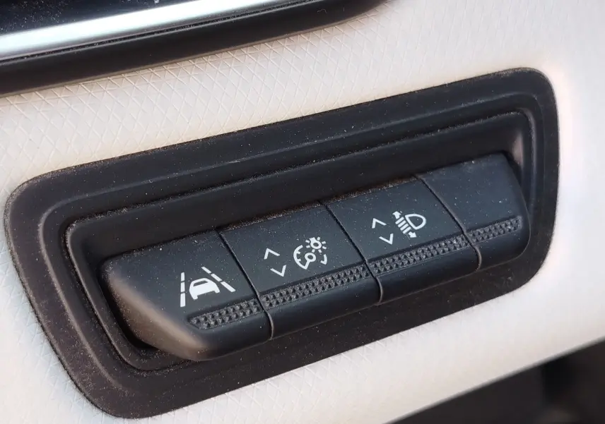 Gros plan sur les boutons de réglage d'assistance à la conduite et d'éclairage dans l'habitacle d'une Renault Clio orange Valencia.