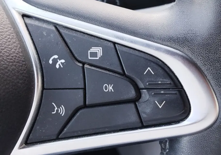 Gros plan sur les commandes multifonctions noires du volant côté gauche de la Renault Clio 1.6 E-Tech hybride orange Valencia 2022.
