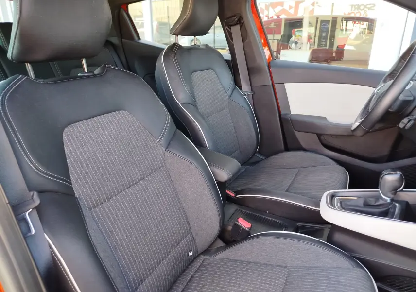 Vue intérieure côté gauche de la Renault Clio 1.6 E-Tech 2022, sièges tissu gris avec surpiqûres blanches et portière orange Valencia.