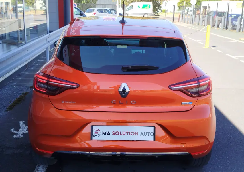 Vue arrière d'une Renault Clio 1.6 E-Tech hybride 140ch Intens 2022 en orange Valencia, avec feux LED distinctifs.