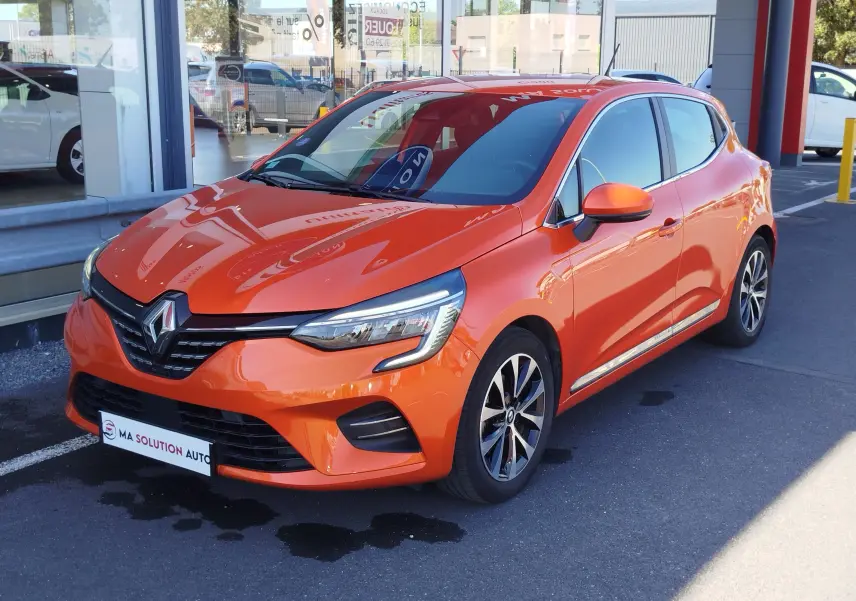 Renault Clio 1.6 E-Tech hybride orange Valencia vue 3/4 avant droit, avec jantes alliage et feux LED distinctifs.