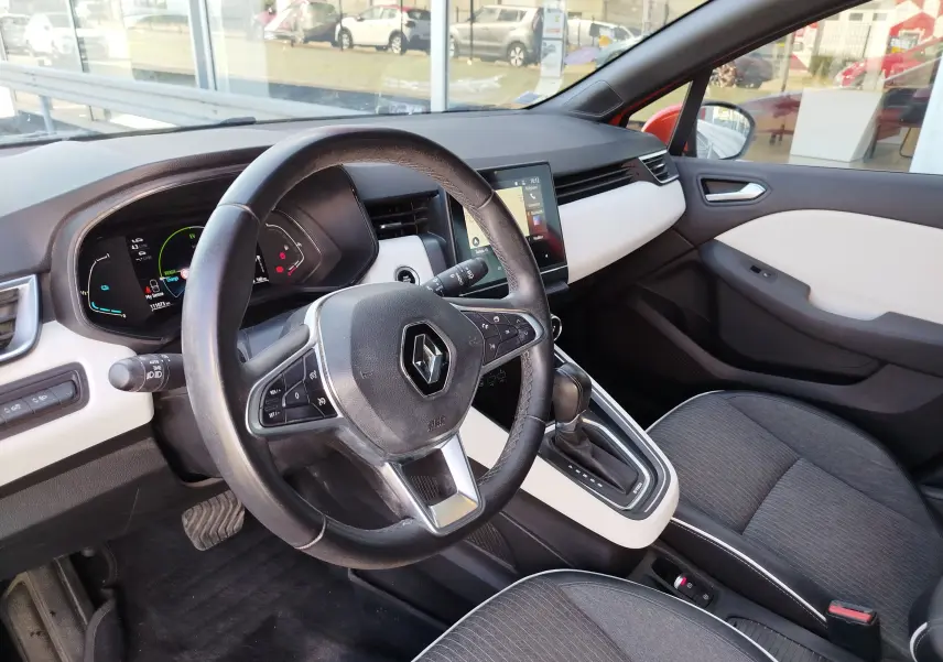 Vue intérieure côté conducteur de la Renault Clio 1.6 E-Tech hybride 2022 avec tableau de bord noir et blanc et volant multifonction.