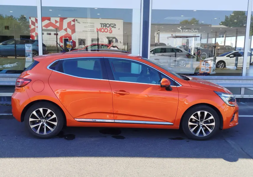 Profil droit d’une Renault Clio 1.6 E-Tech hybride 140ch Intens 2022 en Orange Valencia avec jantes alliage.