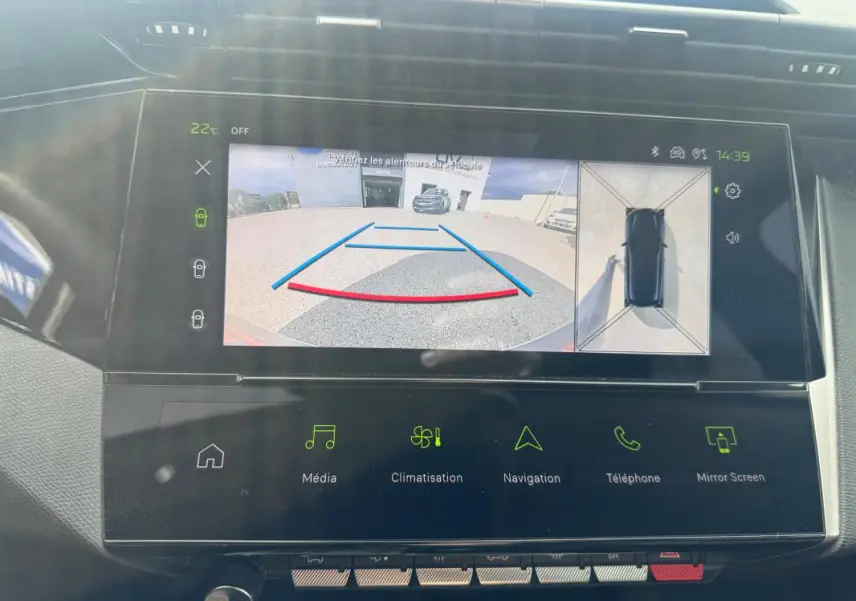 Vue rapprochée du tableau de bord de la Peugeot 308 Hybrid 2025 montrant l'écran de caméra de recul et les commandes tactiles.