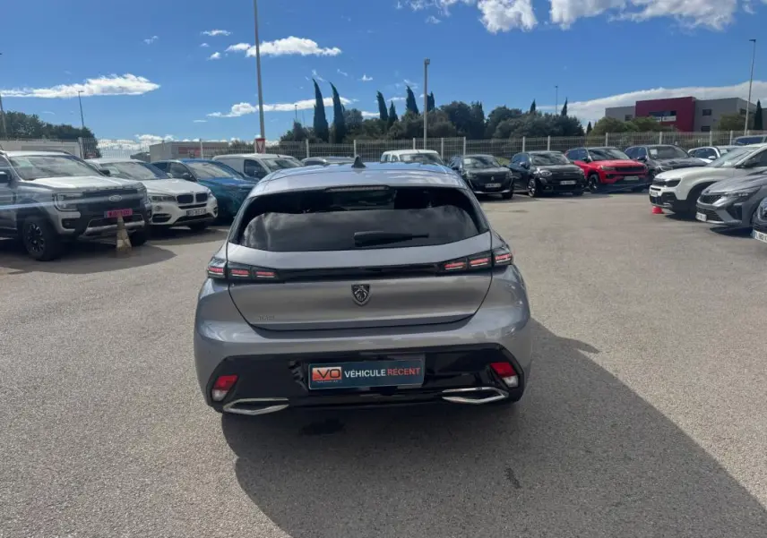 Vue arrière d'une Peugeot 308 Hybrid 145 gris métallisé, avec feux LED distinctifs et double sortie d'échappement intégrée.
