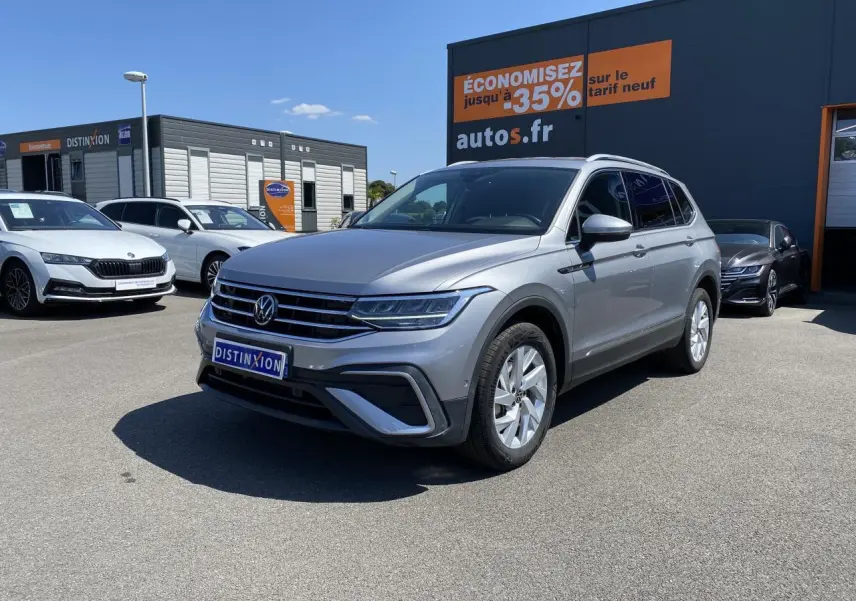 Volkswagen Tiguan Allspace gris argent pyrite métallisé vu en 3/4 avant droit sur parking extérieur.