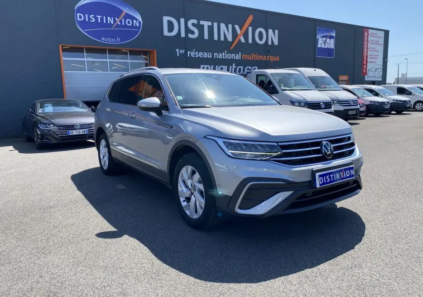 Volkswagen Tiguan Allspace gris argent pyrite métallisé en 3/4 avant droit sur parking extérieur devant concession