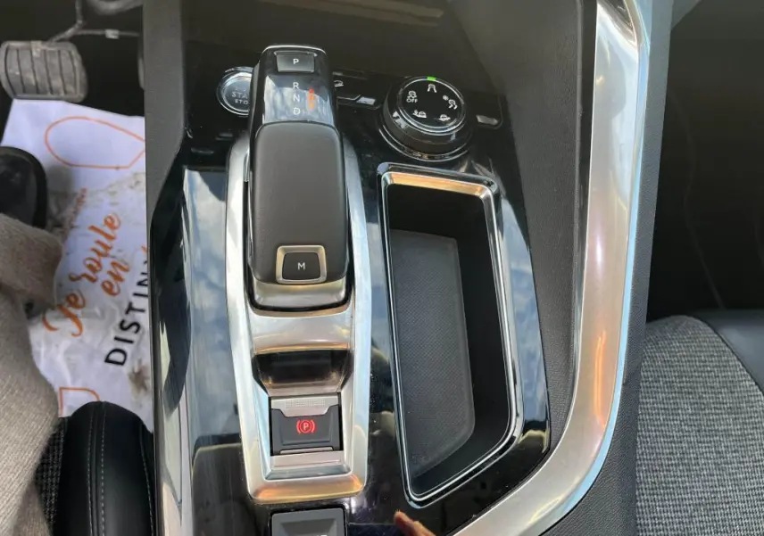 Gros plan sur la console centrale noire brillante du Peugeot 3008 2020 avec levier de boîte auto et bouton sport.