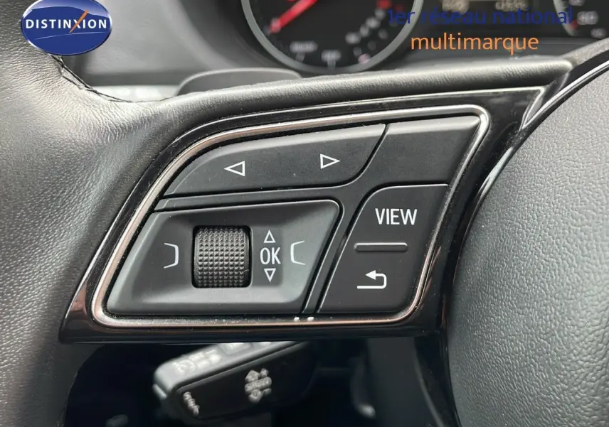 Gros plan sur les commandes au volant noir d'un Audi Q2 35 TFSI S-Line 2023, avec boutons multifonctions visibles.