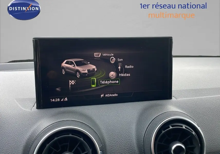 Écran central affichant le menu multimédia avec une image du SUV Audi Q2 noir mito metal en vue latérale intérieure.