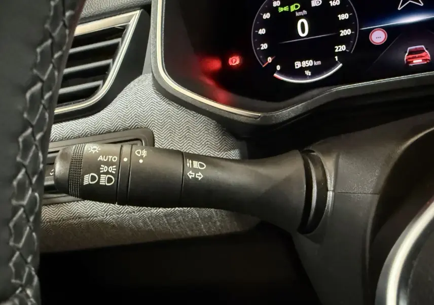 Gros plan sur la commande des phares à gauche du volant dans l’habitacle de la Renault Clio rouge 2024.