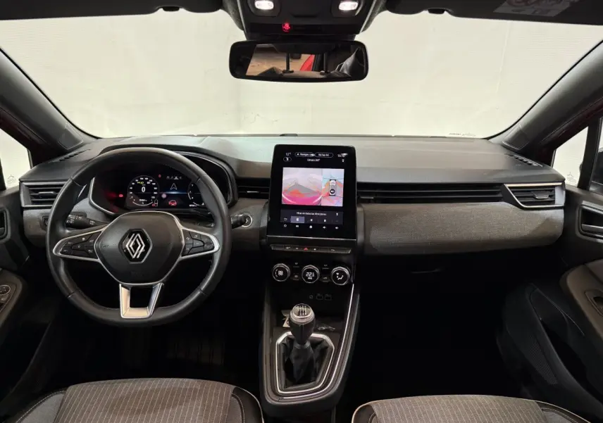 Vue intérieure avant de la Renault Clio Techno TCe 90 2024, tableau de bord avec écran tactile vertical et volant multifonctions.