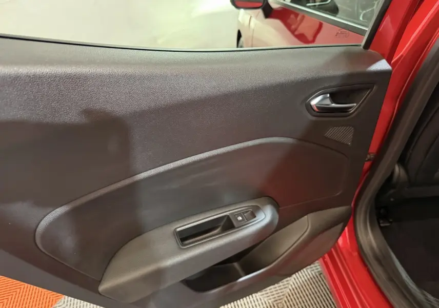 Vue intérieure sur la porte arrière gauche noire avec poignée et bouton de lève-vitre d’une Renault Clio rouge 2024.