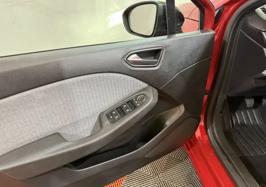 Vue intérieure côté gauche de la porte avant rouge de la Renault Clio 2024 avec commandes des vitres et rétroviseur.