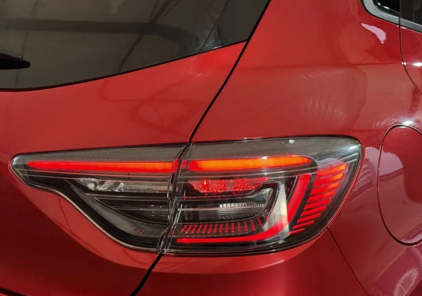 Gros plan sur le feu arrière droit rouge d’une Renault Clio Techno TCe 90 2024 rouge, avec détails lumineux modernes.
