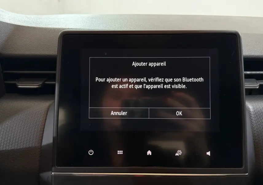 Écran tactile central du tableau de bord de la Renault Clio Business blanc, affichant un message Bluetooth.
