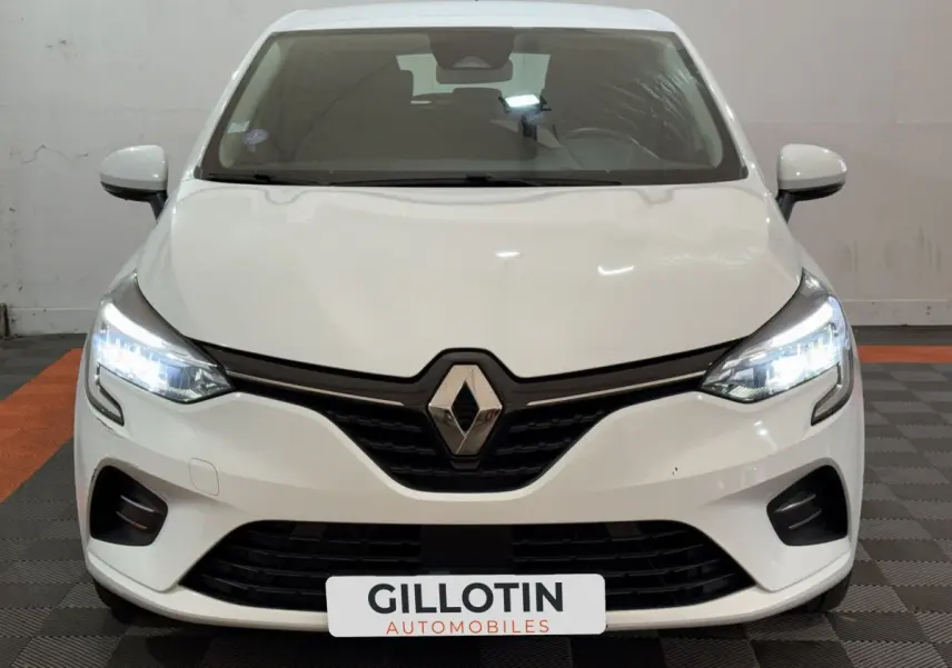 Vue frontale d'une Renault Clio Business blanche de 2021 avec phares LED allumés et calandre noire distinctive.