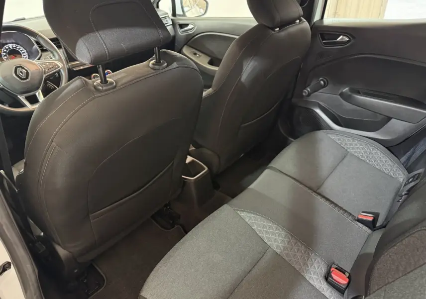 Vue arrière intérieure côté droit de la Renault Clio Business blanche, montrant les sièges arrière et dossier avant noir.