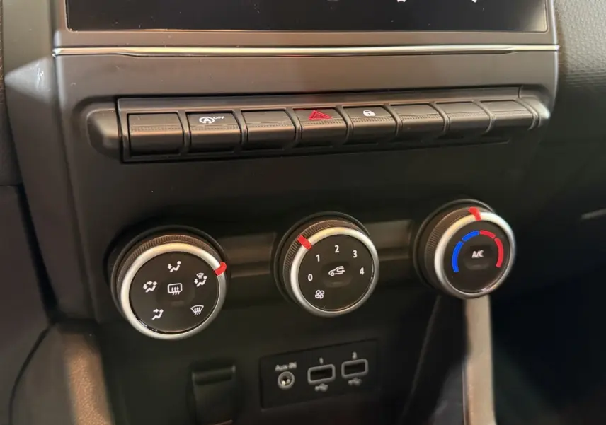 Gros plan sur les commandes de climatisation et ventilation de la Renault Clio Business blanche, tableau de bord noir.