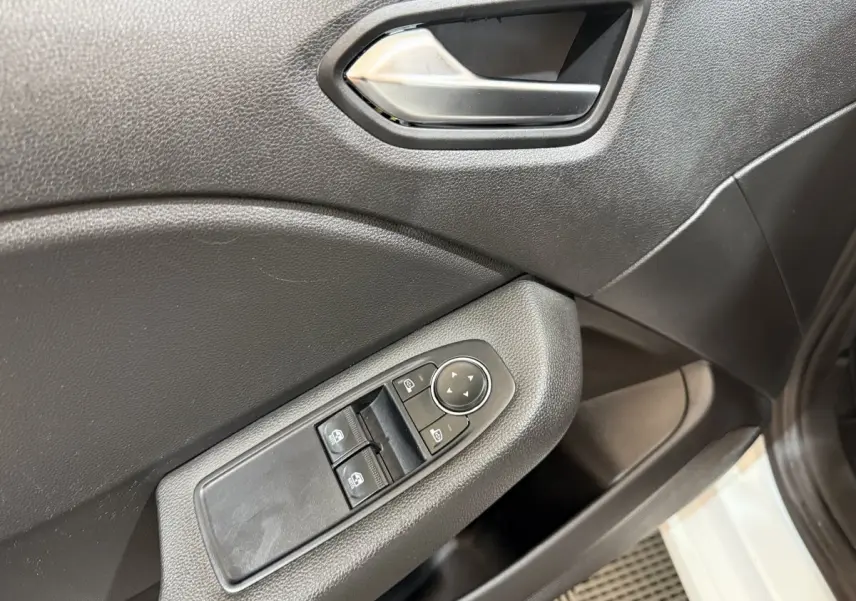 Vue rapprochée de la porte côté conducteur d'une Renault Clio blanche 2021, avec commandes électriques des vitres et rétroviseurs.
