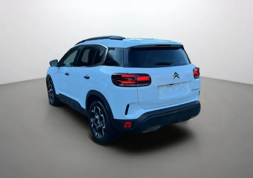 Vue 3/4 arrière gauche d’un Citroën C5 Aircross blanc okénite avec vitres surteintées et jantes alu 18 pouces.
