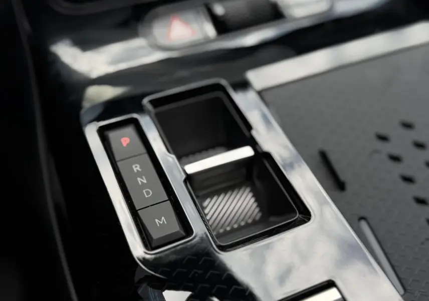 Gros plan sur la console centrale noire brillante du Citroën C5 Aircross hybride avec sélecteur de vitesses électronique.
