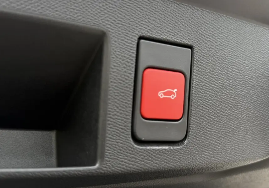 Gros plan sur le bouton rouge d'ouverture électrique du hayon intérieur du Citroën C5 Aircross blanc et noir.