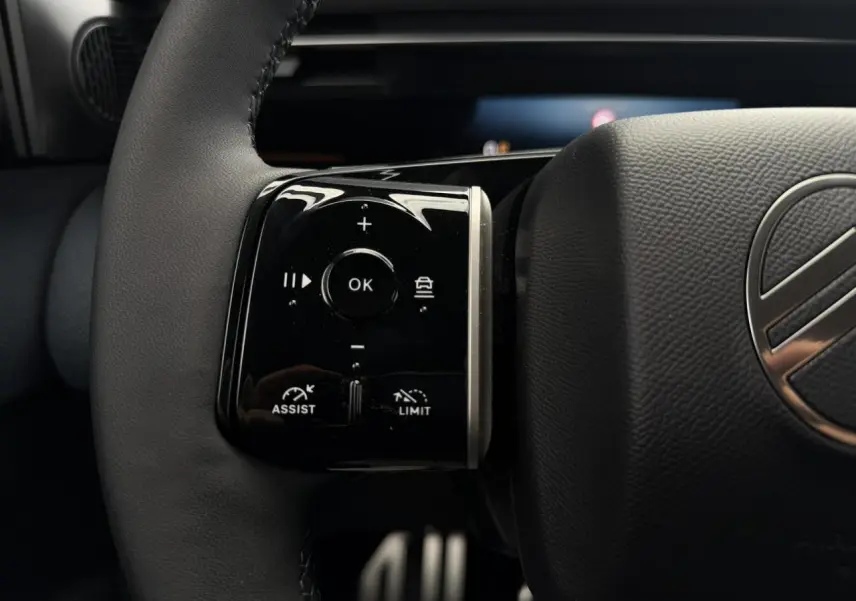 Gros plan sur les commandes noires brillantes au volant cuir du Citroën C5 Aircross hybride 2026.