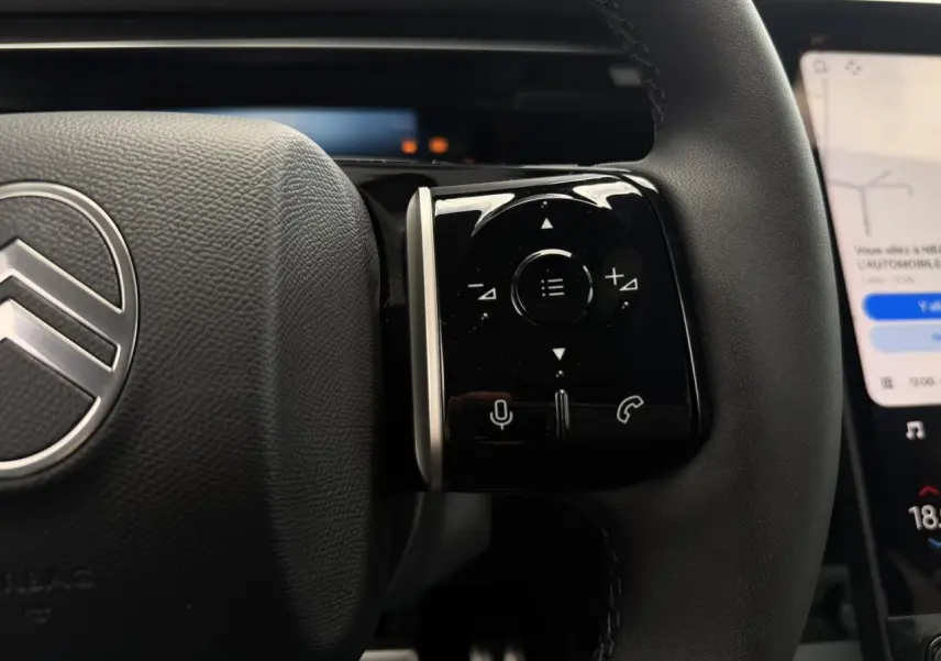 Gros plan sur le côté droit du volant noir du Citroën C5 Aircross 2026 avec commandes tactiles et logo argenté.