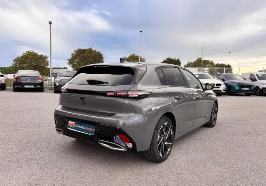 Vue 3/4 arrière droite d'une Peugeot 308 gris métallisé avec jantes alliage 17 pouces et vitres teintées.