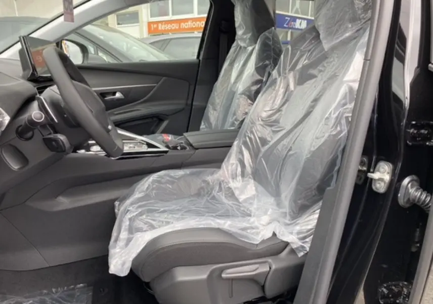 Vue intérieure côté conducteur du Peugeot 3008 noir Perla Nera 2021, sièges protégés par housses plastiques.