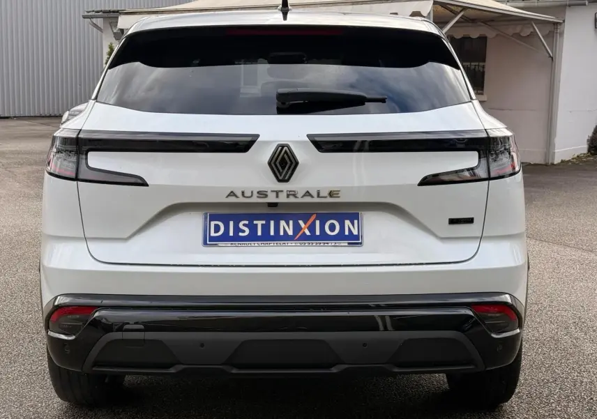 Vue arrière d'un Renault Austral blanc nacré avec toit noir, mettant en valeur ses feux horizontaux et son logo central.