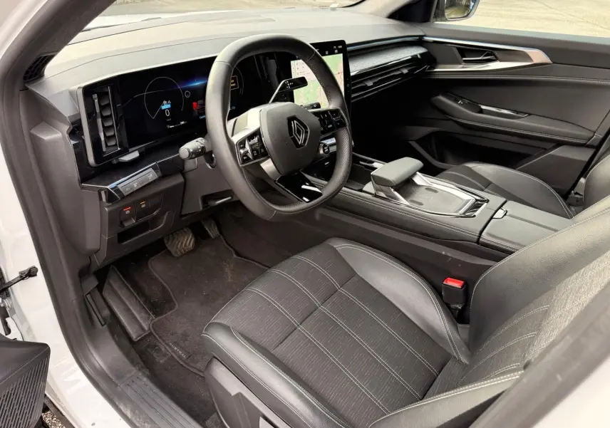 Intérieur du Renault Austral E-Tech 200 hybride, vue côté conducteur, avec tableau de bord numérique et sièges noirs en tissu et cuir.