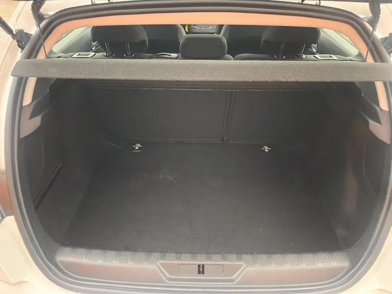 Coffre ouvert vu de l'arrière d'une Peugeot 308 blanc banquise, montrant l'espace de chargement vide et la plage arrière.