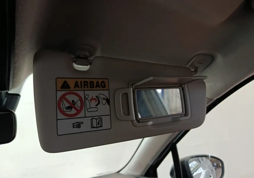 Vue intérieure rapprochée du pare-soleil côté conducteur avec miroir et avertissement airbag dans une Renault Clio gris clair.