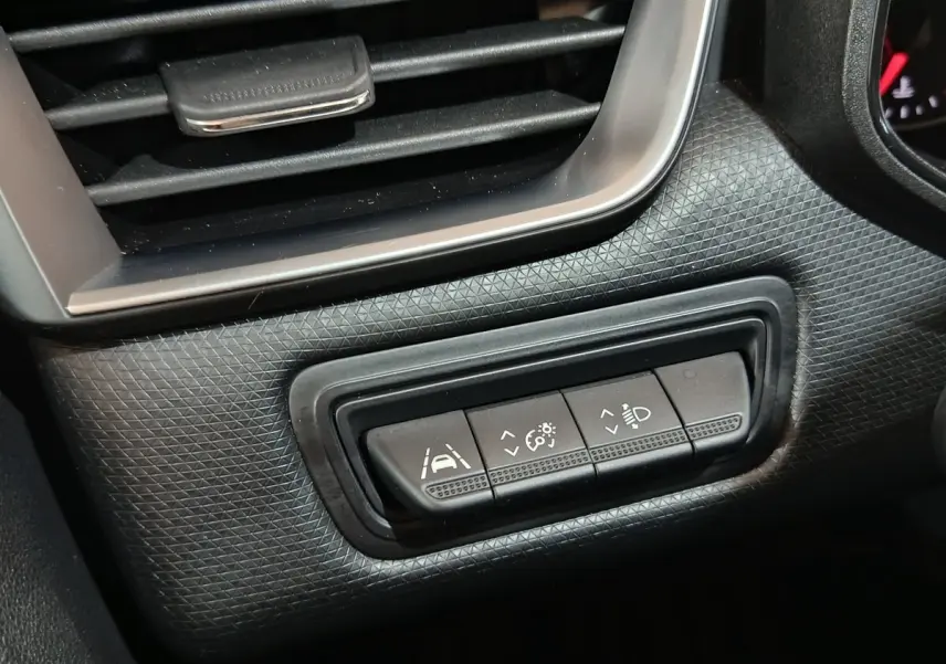 Gros plan sur les commandes d’aide à la conduite de la Renault Clio Equilibre TCe 90 2023, tableau de bord noir texturé.