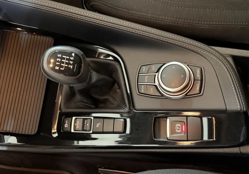 Vue rapprochée de la console centrale noire du BMW X2 sDrive18i 2023 avec levier de vitesse manuel et molette de sélection.
