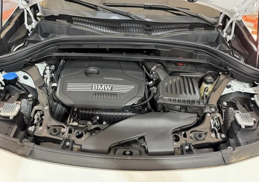 Moteur TwinPower Turbo BMW visible sous le capot ouvert d’un BMW X2 blanc, vue de face rapprochée.