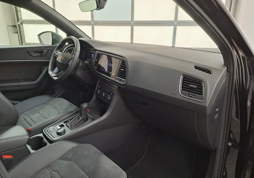 Intérieur du CUPRA Ateca 2024 noir magique, vue côté conducteur, tableau de bord moderne avec écran tactile central.