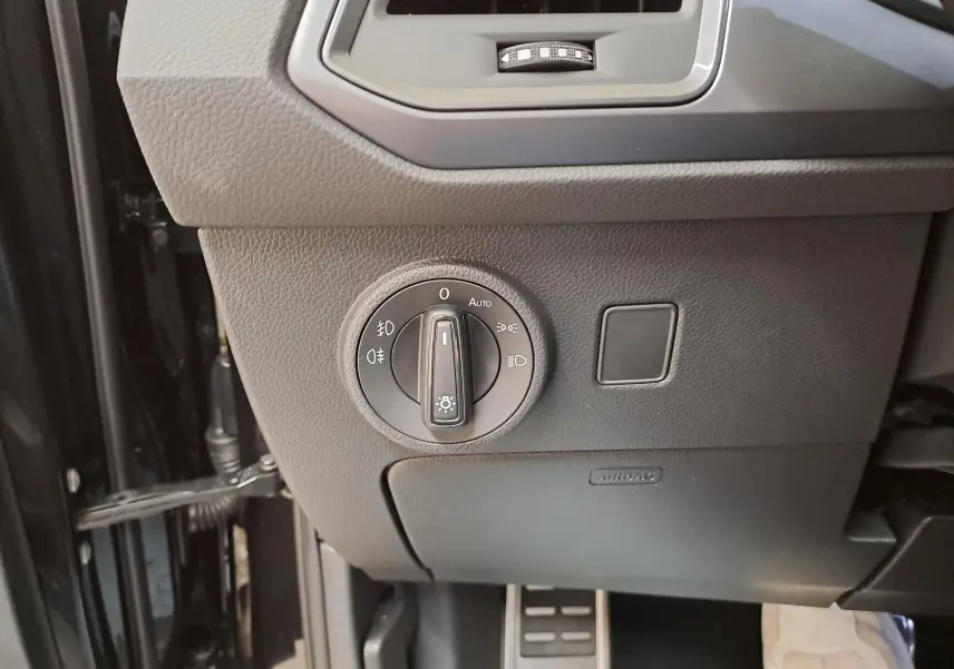 Gros plan sur le bouton de commande des phares à gauche du tableau de bord du CUPRA Ateca Noir Magique 2024.