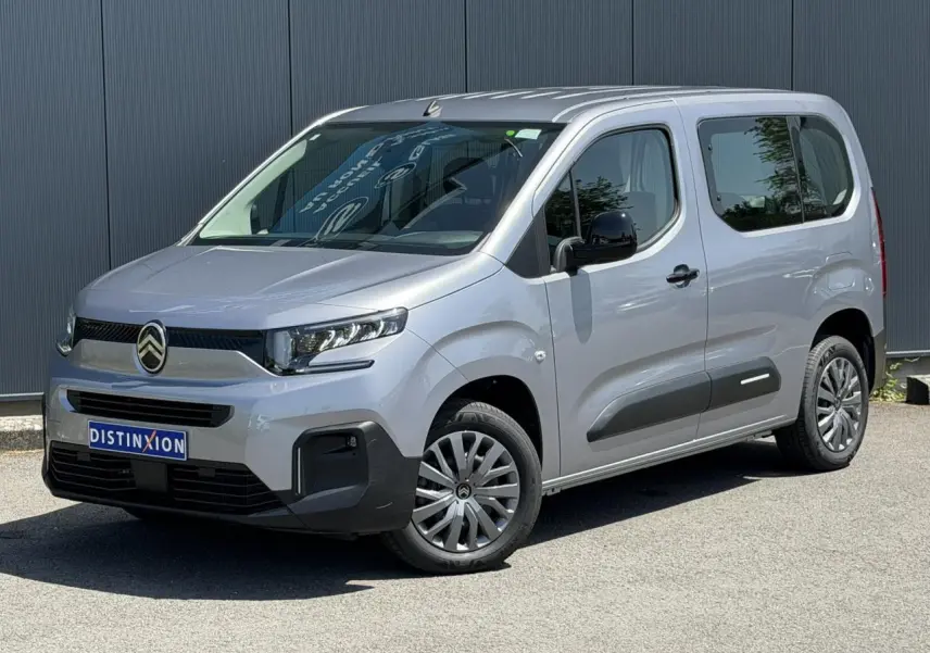 Vue 3/4 avant droit du Citroën Berlingo ë-136 gris Artense avec jantes tôles et protections latérales noires.