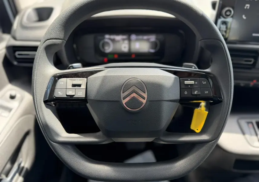 Vue rapprochée du volant multifonction noir du Citroën Berlingo ë-136 2025 avec commandes intégrées et logo central.