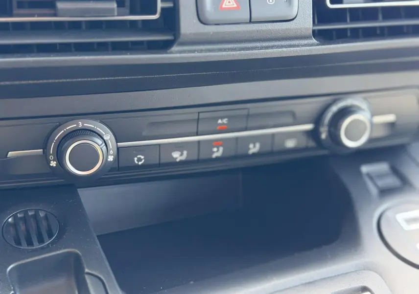 Gros plan sur la console centrale du Citroën Berlingo ë-136 gris Artense, montrant les commandes de climatisation et ventilation.