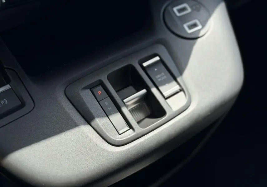 Gros plan sur la console centrale grise du Citroën Berlingo ë-136, montrant la commande de boîte automatique et frein de stationnement.