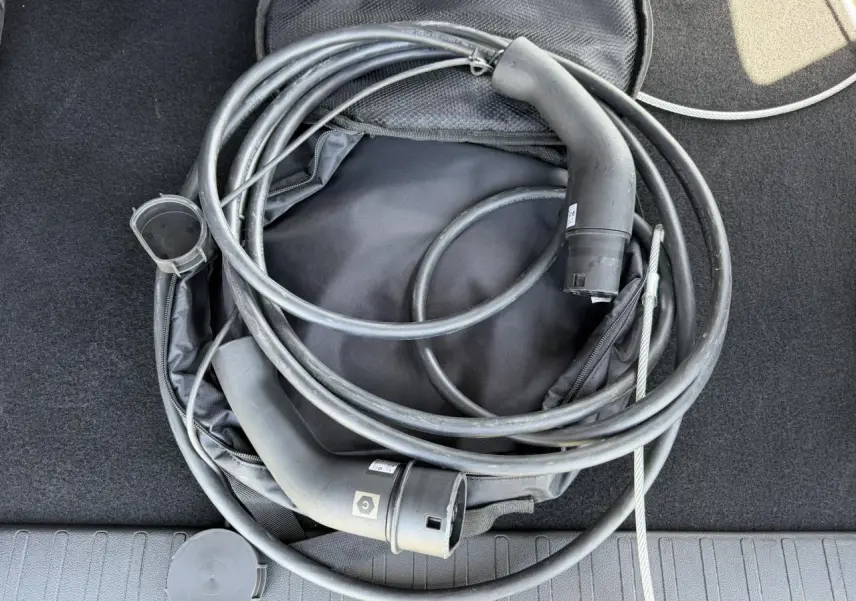 Câble de recharge électrique noir enroulé dans le coffre d’un Citroën Berlingo gris Artense.
