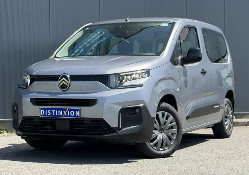 Vue 3/4 avant du Citroën Berlingo ë-136 gris Artense avec jantes tôles et pare-chocs noirs contrastés.